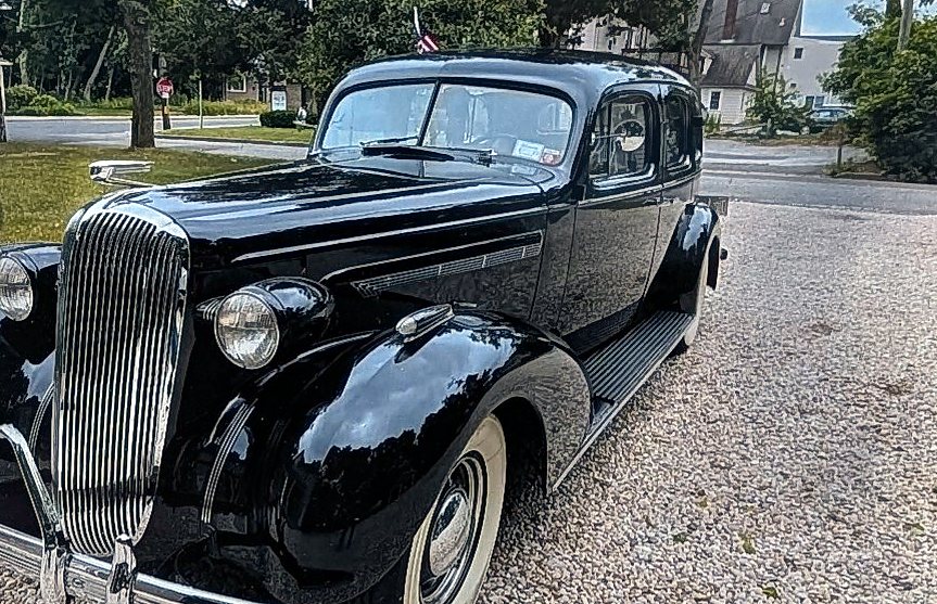 Chrome waterfall grille, headlamp and front fender of a black 1936 Buick Roadmaster